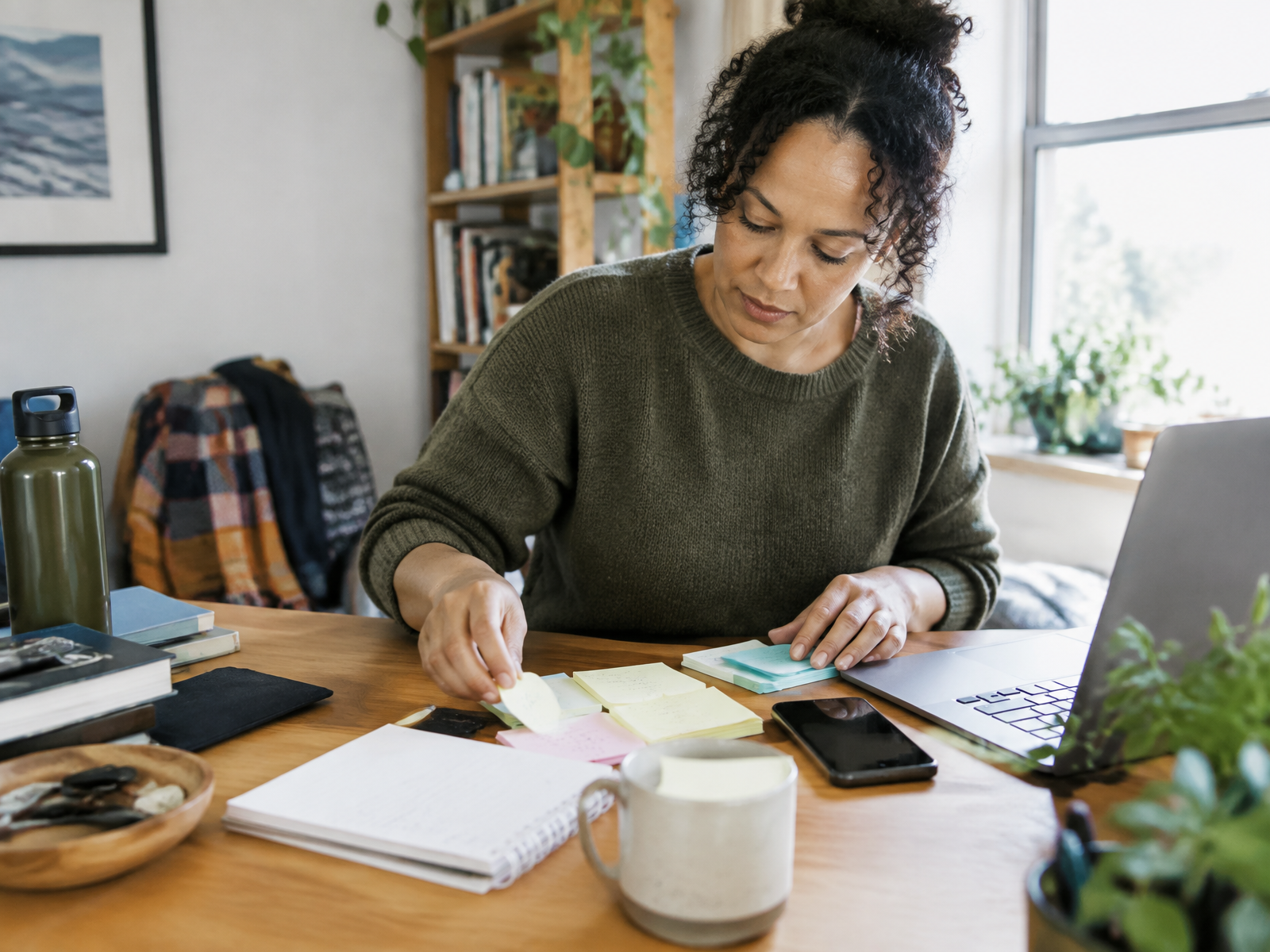 A woman organizing notes at a desk while working in daylight
