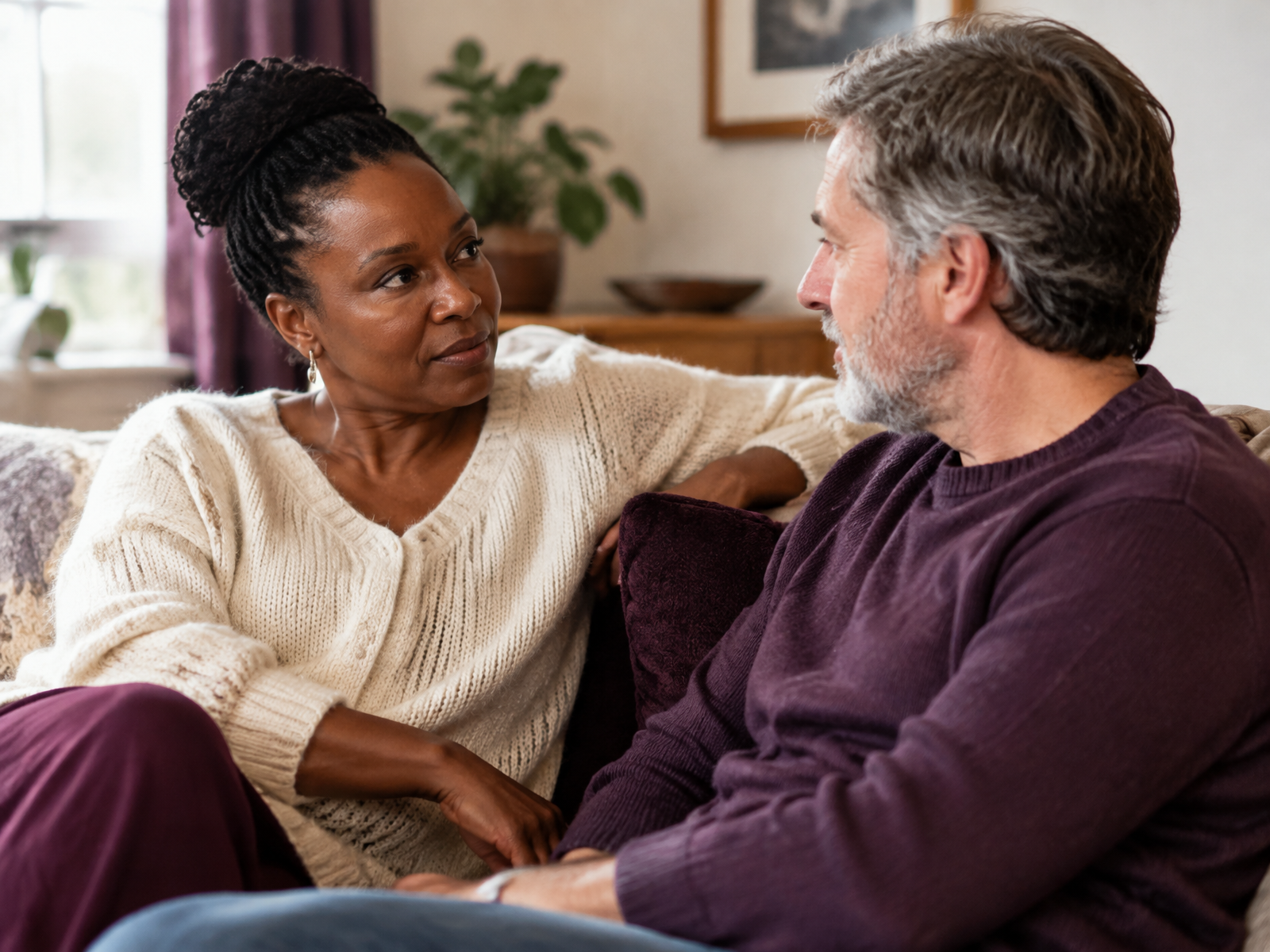 A couple talking and listening to each other on a sofa at home