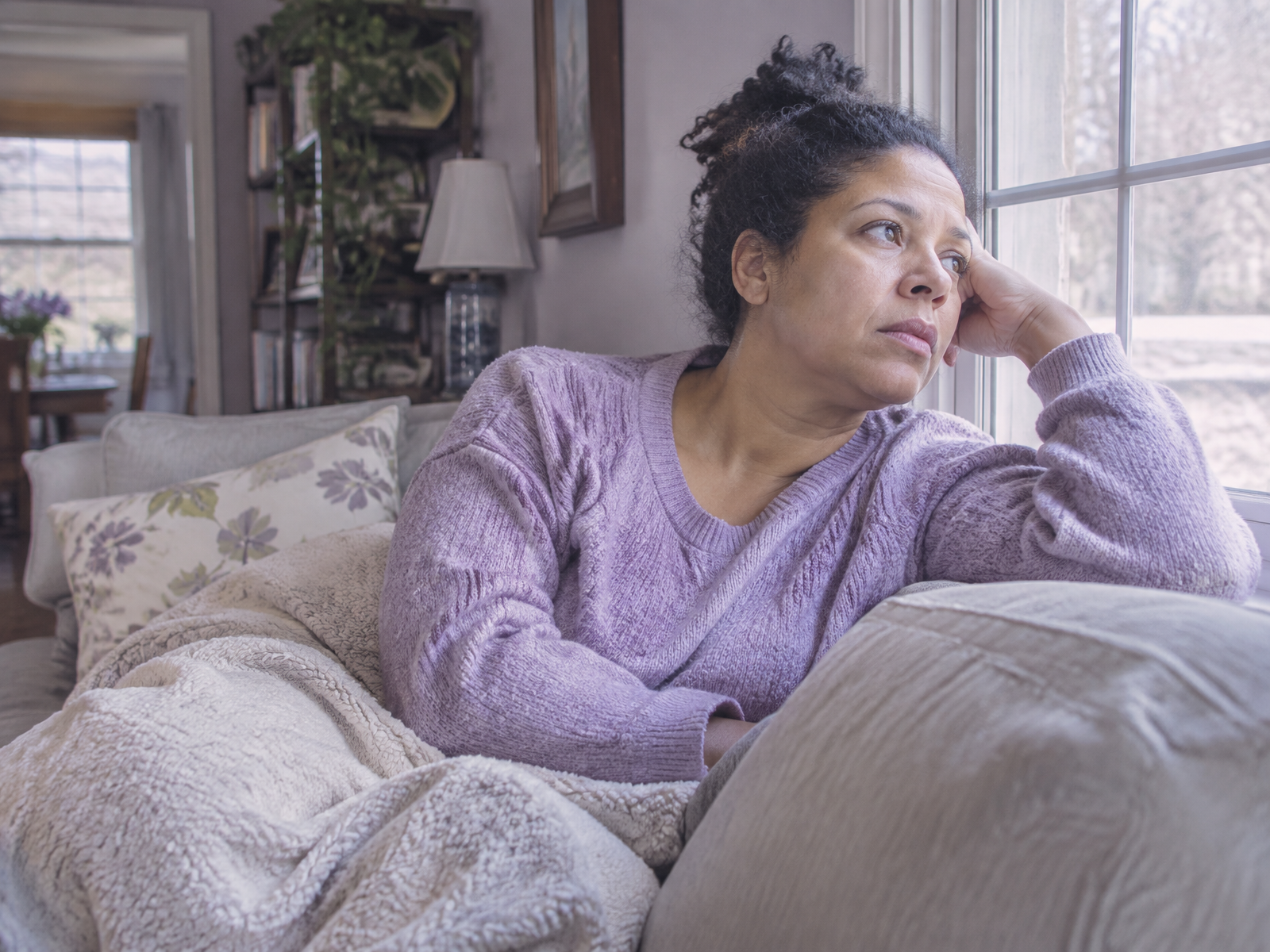 A tired woman sitting quietly on her bed beside a closed notebook at night